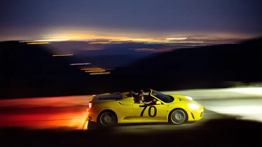 Ferrari F430 montant une course de côte au crépuscule, pilote visible