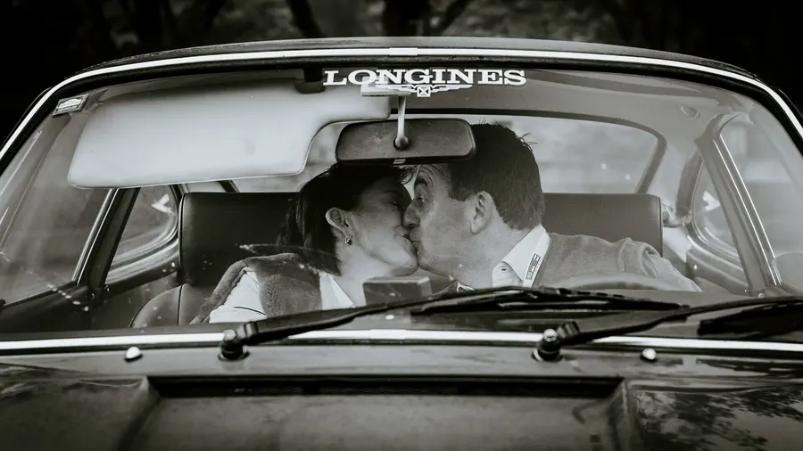 Portrait en noir et blanc d'un couple s'embrassant dans une voiture ancienne lors d'un rallye