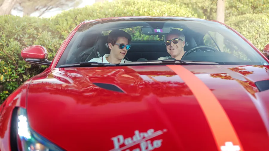 Père et fils souriant à bord d'une Ferrari lors d'un rallye père-fils