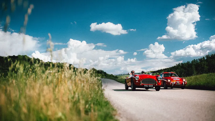 Ferrari et Lancia classiques roulant le long d'une route de campagne lors de la Mille Miglia