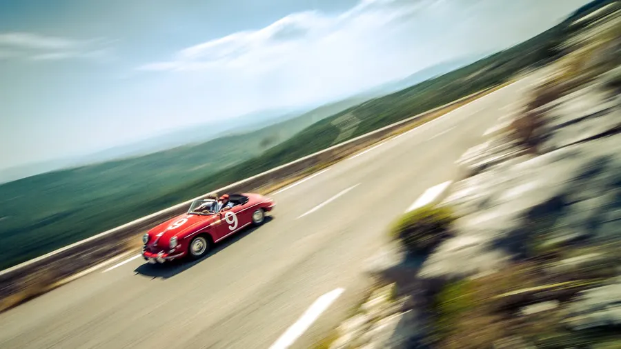 Vue aérienne d'une Porsche 356 Speedster rouge sur une route de montagne