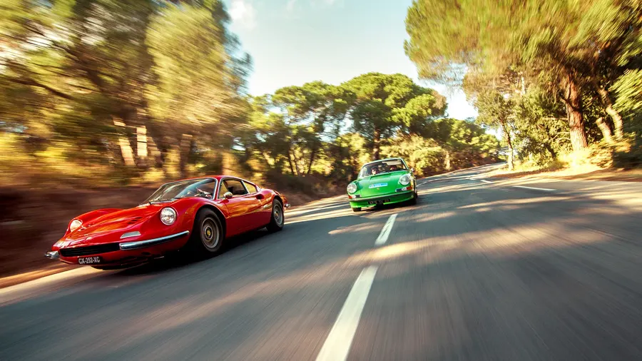 Ferrari Dino et Porsche 911 roulant ensemble sur une route bordée d'arbres