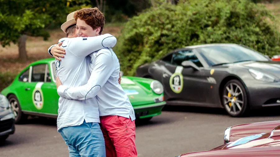 Père et fils s'enlaçant chaleureusement lors d'un rallye de voitures anciennes