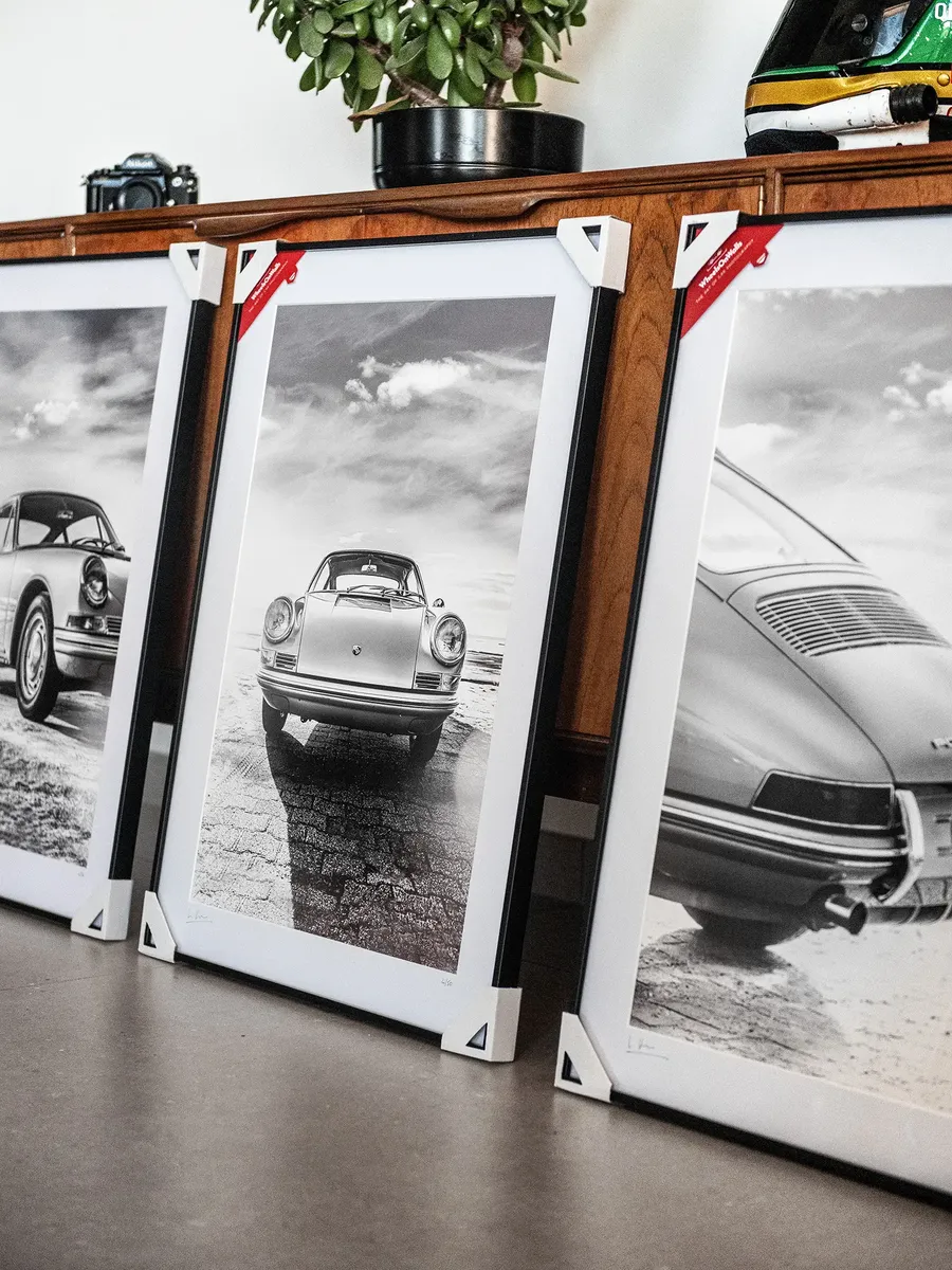 Collection de tirages d'art encadrés de Porsche 911 posés contre un meuble